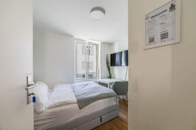 a white bedroom with a bed and a window at HRE Apartments St Gallen City Center in St. Gallen