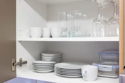 a white cabinet filled with plates and glassware at Klara 1022 - Olma, Spital, Uni St- Gallen in St. Gallen