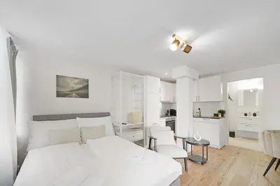 a white bedroom with a bed and a kitchen at Book2Stay - modernes Studio OLMA-Areal in St. Gallen