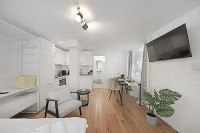 a white living room with a desk and a tv at Book2Stay - modernes Studio OLMA-Areal in St. Gallen