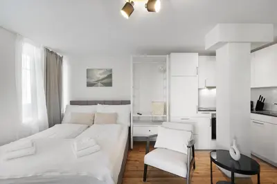 a white bedroom with a bed and a chair at Book2Stay - modernes Studio OLMA-Areal in St. Gallen