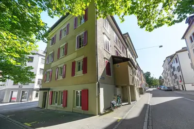 a green building with red doors on a street at Book2Stay - modernes Studio OLMA-Areal in St. Gallen