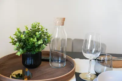 a table with a bottle and a plant and wine glasses at book2stay modernes Apartment OLMA-Areal in St. Gallen