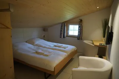 a small bedroom with a bed and a chair at Hotel Kaubad in Appenzell