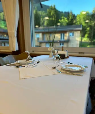 a table with plates and glasses and a window at Hotel Kaubad in Appenzell