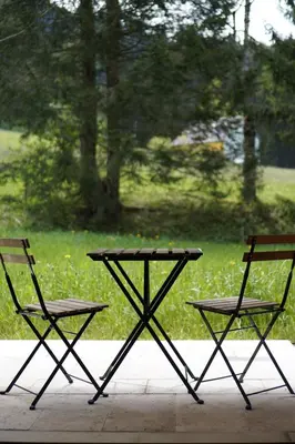 a picnic table and two chairs sitting next to a field at Hotel Kaubad in Appenzell