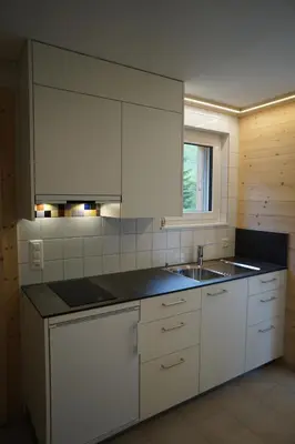 a kitchen with white cabinets and a sink and a window at Hotel Kaubad in Appenzell