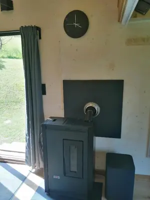 a clock on a wall with a stove in a room at Tiny House im Grünen in Sankt Margrethen
