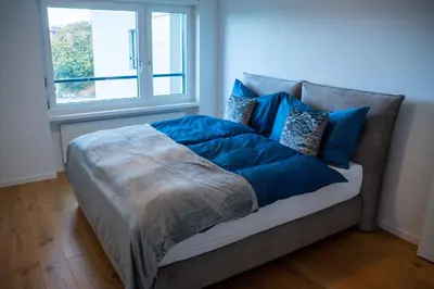 a bed with blue pillows on a couch with a window at Seenähe 300 Meter 126 qm Wohnfläche 6 Betten in Rorschacherberg