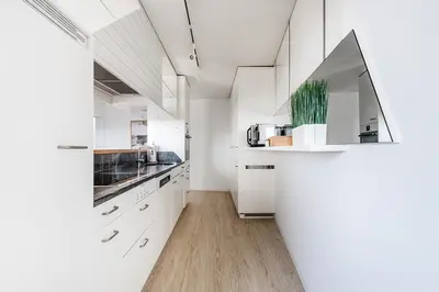 a white kitchen with white cabinets and a wooden floor at SOHO PENTHOUSE !Gratis Parken, Free Parking! in Kreuzlingen