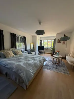 a bedroom with a large bed and a living room at MTL Schweiz Apartments in Kreuzlingen