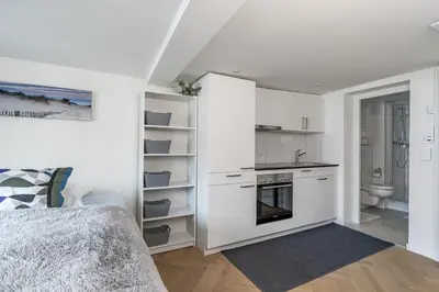 a white room with a kitchen and a bed at Ferien Studio Wohnung Altstadt Multergasse 20 in St. Gallen
