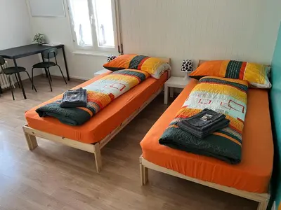 two twin beds in a room with a table at 02 - Gästehaus Erika - Hundwil - Appenzellerland in Hundwil