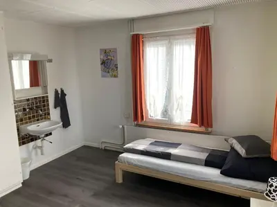 a bedroom with a bed and a sink and a window at 08 - Gästehaus Erika - Hundwil - Appenzellerland in Hundwil