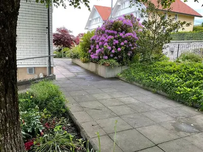 a garden with purple flowers and a sidewalk at 12 - Gästehaus Erika - Hundwil - Appenzellerland in Hundwil