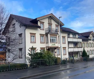 a large white house with a black fence at 12 - Gästehaus Erika - Hundwil - Appenzellerland in Hundwil