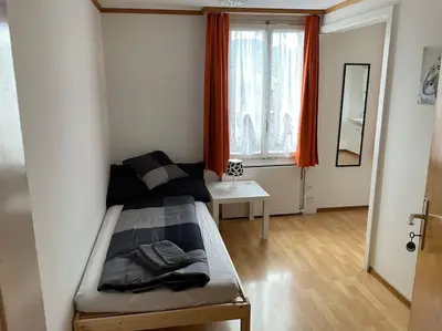 a bedroom with a bed and a window with red curtains at 15 - Gästehaus Erika - Hundwil - Appenzellerland in Hundwil