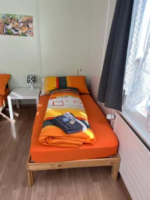 a bed with an orange blanket on it in a room at 20 - Gästehaus Erika - Hundwil - Appenzellerland in Hundwil