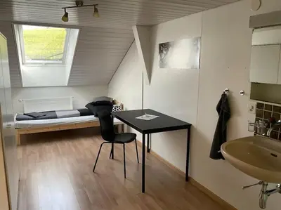 a bedroom with a bed and a table and a sink at 23 - Gästehaus Erika - Hundwil - Appenzellerland in Hundwil