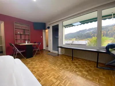 a room with a large window and a table and chairs at Wildhaus Ferienwohnung in Wildhaus