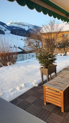 a wooden bench sitting on a deck in the snow at Wildhaus Ferienwohnung in Wildhaus
