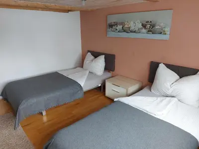 a small room with two beds and a window at Bauernhaus Hinterbühle in Wolfhalden