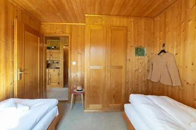 a bedroom with wooden walls and two beds and a closet at Dorea in Wildhaus