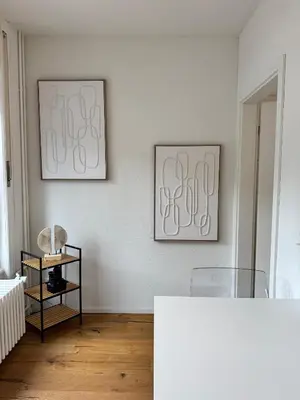 two framed art on a white wall in a room at Apartment im Zentrum St Gallen in St. Gallen