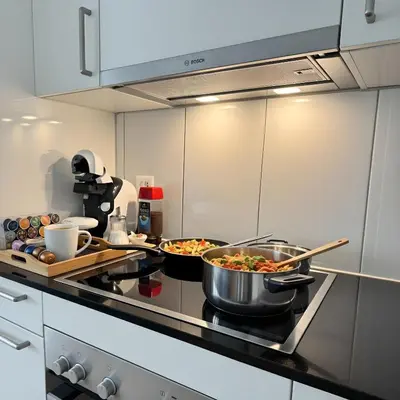 a kitchen with two pans of food on a stove at Zentrales Apartment St Gallen an der Olma in St. Gallen