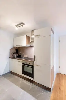 a kitchen with white cabinets and a stove and a refrigerator at Nachhaltig Wohnen im 1, Stock, gratis Parkplatz! in St. Gallen