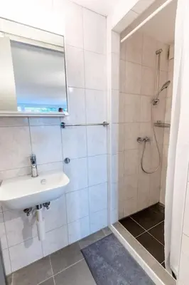 a white bathroom with a sink and a shower at Nachhaltig Wohnen im 1, Stock, gratis Parkplatz! in St. Gallen