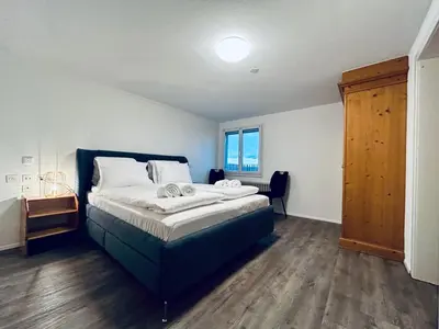 a bedroom with a large bed and a wooden floor at Private room with Bathroom and Lake View in Guest House in Heiden