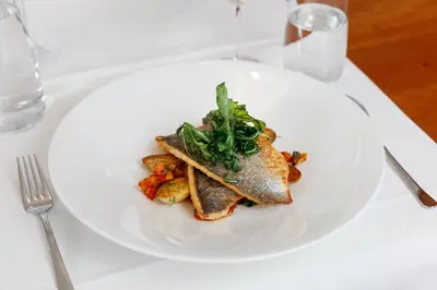 a white plate with a fish dish on a table at Hotel Krone Speicher in Speicher