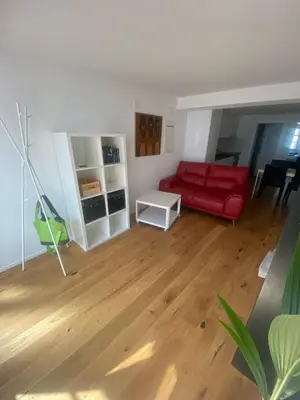 a living room with a red couch and a wooden floor at Zentrales Schloss Apartment in Arbon
