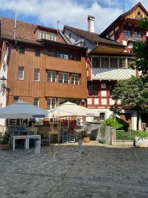 a building with tables and umbrellas in front of it at Gemütliches Apartment am Schloss in Arbon