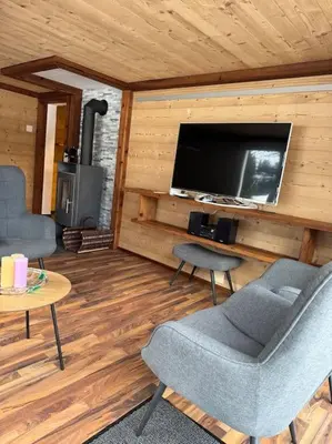 a living room with a tv and a chair and a table at Heimelige Wohnung auf der Schwägalp in Urnäsch