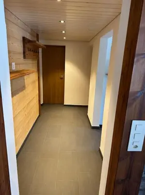 an empty hallway with a door and a tile floor at Heimelige Wohnung auf der Schwägalp in Urnäsch
