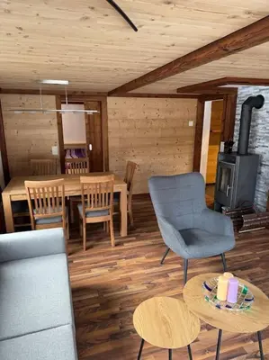 a living room with a table and chairs and a stove at Heimelige Wohnung auf der Schwägalp in Urnäsch