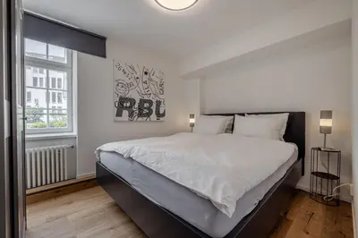 a kitchen with white cabinets and black chairs at Ferienwohnungen Webergasse 23 in St. Gallen