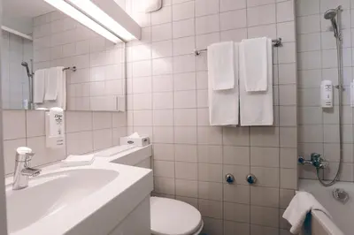 a bathroom with a sink and a toilet and a tub at Hotel Thurgauerhof Self-Check-in in Weinfelden
