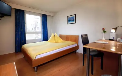 a bedroom with a bed and a desk and a table at Hotel Thurgauerhof Self-Check-in in Weinfelden