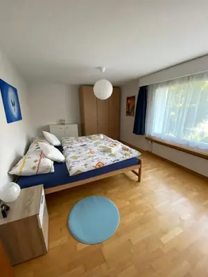 a bedroom with a bed and a blue rug at 3 Zimmer-Ferienwohnung in der Rüti in Herisau