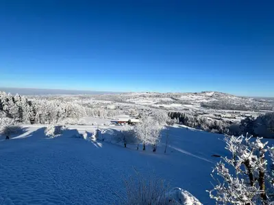 a snow covered field with a house in the distance at 3 Zimmer-Ferienwohnung in der Rüti in Herisau