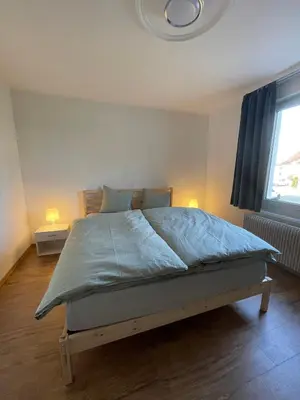 a bedroom with a bed with blue sheets and a window at Charmante Ferienwohnung im Oberthurgau in Amriswil
