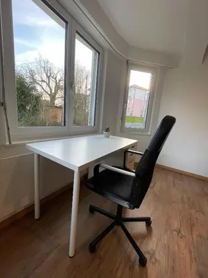 a white desk and a black chair in a room with windows at Charmante Ferienwohnung im Oberthurgau in Amriswil