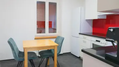a small kitchen with a wooden table and two chairs at Ninety Apartments in St. Gallen