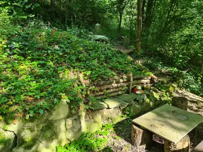 a stone wall with a bench and a table at Auszeitoase am Wald und Bach in Kradolf