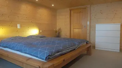 a bedroom with a bed in a wooden wall at Mällis Heimetli in Urnäsch