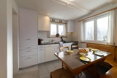 a kitchen with white cabinets and a wooden table at Eldanora in Wildhaus