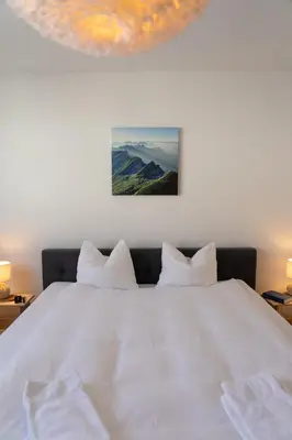 a bedroom with a bed with white sheets and mountains at Saentis in Wildhaus